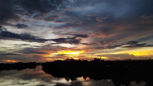 Scenic view of lake against dramatic sky during sunset