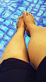 Low section of woman relaxing in swimming pool