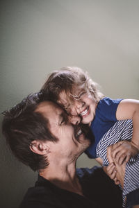 Portrait of happy daughter with smiling father against wall