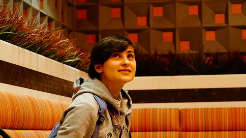 Smiling young woman looking away in auditorium