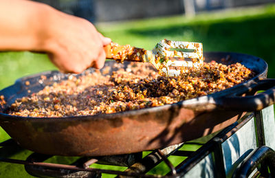 Close-up of man preparing food on barbecue grill in yard