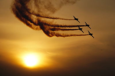 Low angle view of silhouette airplane flying against sky during sunset