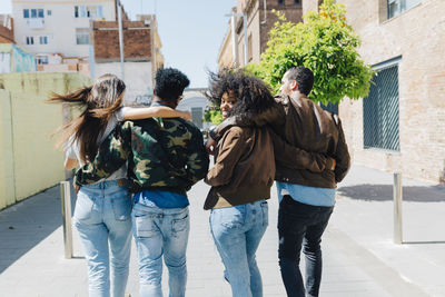 Rear view of stylish friends walking on urban street