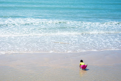 Rear view of girl on shore at beach