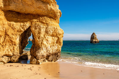 Rock formation on beach against sky