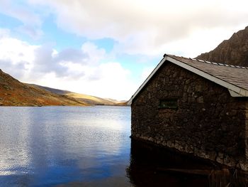 Building by lake against sky