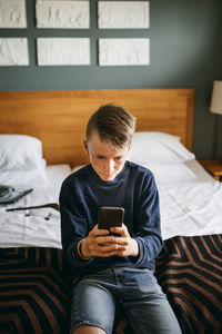 Boy in hotel room checking his mobile