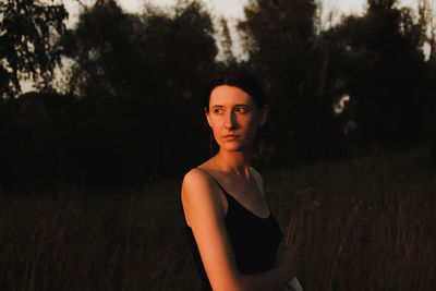 Portrait of woman standing on field against trees