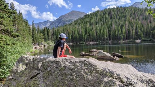 Man standing on rock by lake against mountains