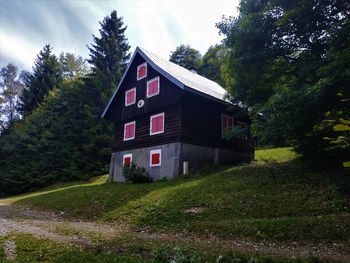 View of cottage by house in forest