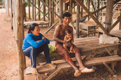 Full length of shirtless man sitting on wood