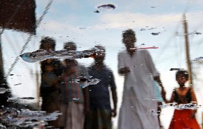 Reflection of people on puddle during monsoon