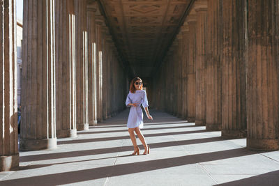 Smiling young woman standing amidst columns