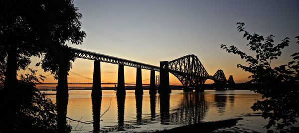 Low angle view of forth railway bridge over river against sky during sunset
