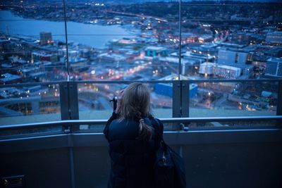 Rear view of woman looking at illuminated cityscape