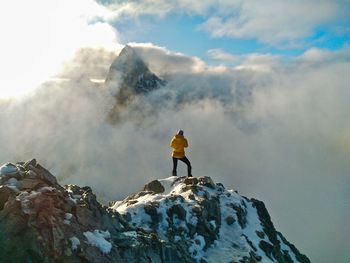 Rear view of man standing on rock against sky