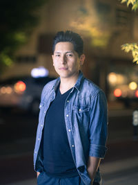 Portrait of young man standing in city at night