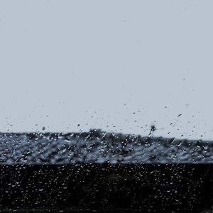 Close-up of wet glass against sky