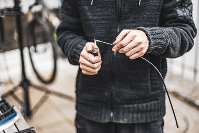 A young man is repairing a bicycle in the backyard of the house.