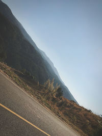 Road by mountain against clear sky