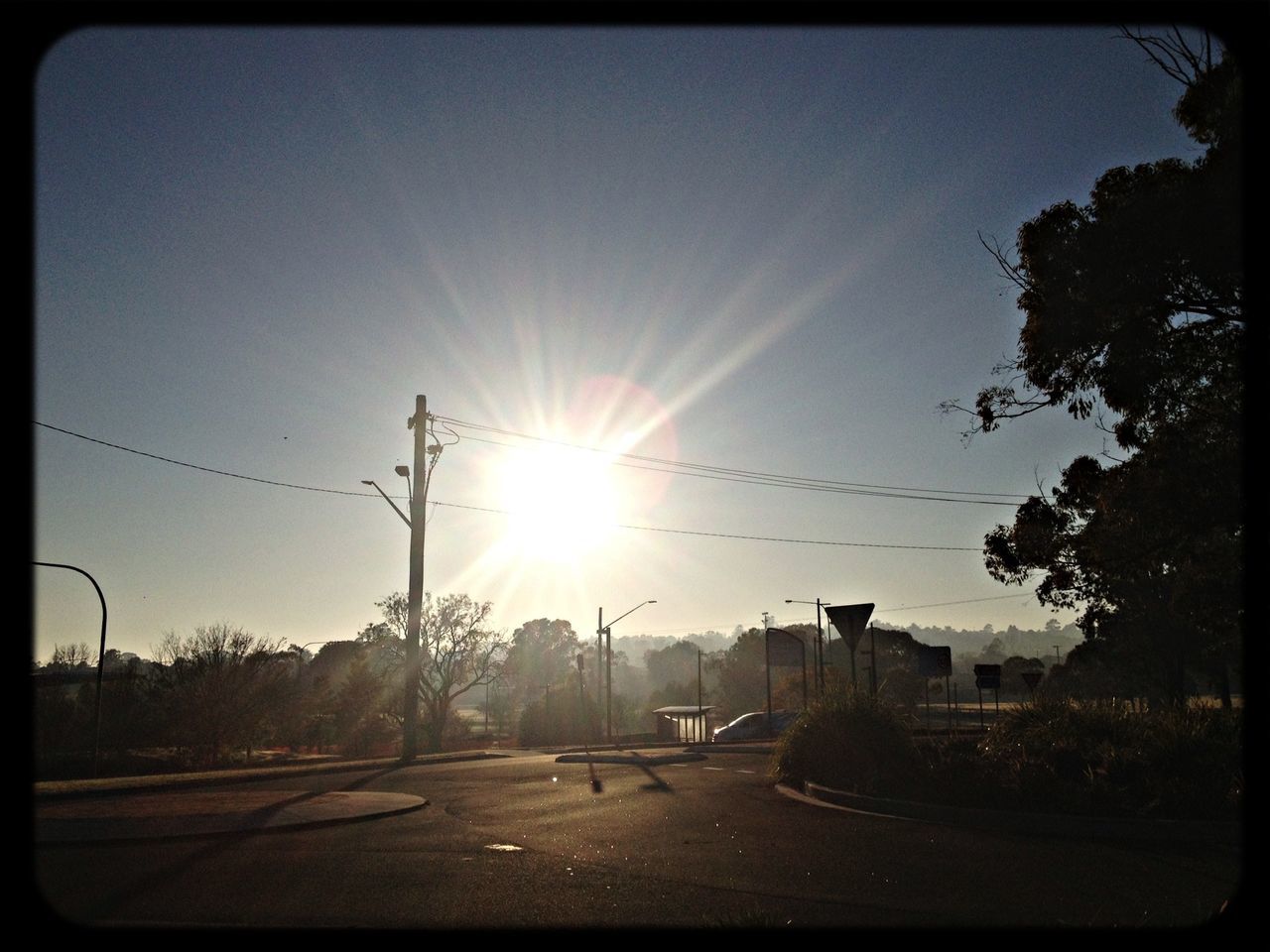 sun, sunlight, sunbeam, lens flare, clear sky, tree, road, transfer print, silhouette, sky, sunset, transportation, built structure, building exterior, street, the way forward, auto post production filter, sunny, tranquility, landscape