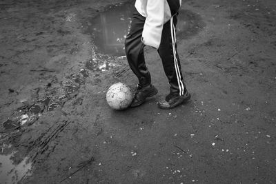 Low section of man playing soccer by puddle on field