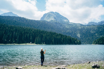 Man standing by lake against mountains