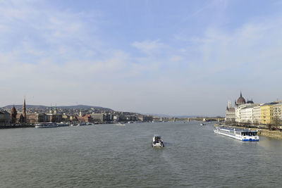 View of buildings by river against sky in city