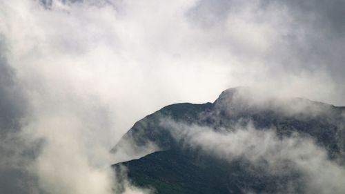 Low angle view of smoke emitting from mountain against sky