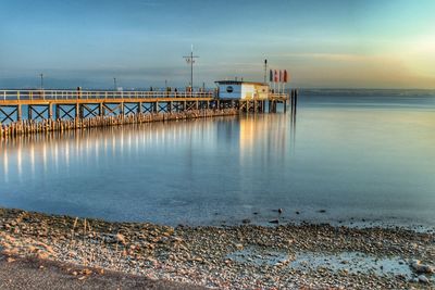 Pier over sea against sky at sunset