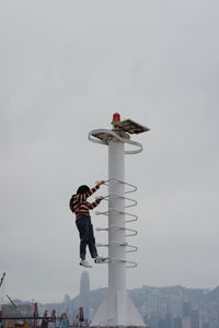 Man with umbrella against sky in city