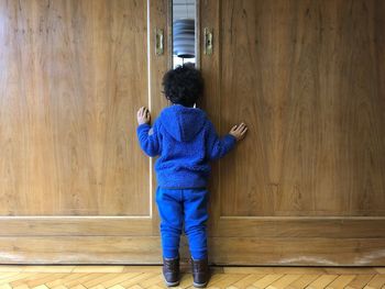 Rear view of woman standing against wooden wall