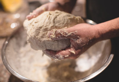 Cropped hands of man preparing dough on table