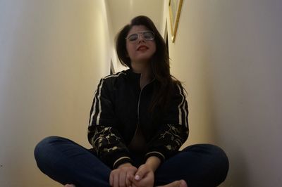 Young woman wearing sunglasses sitting at home