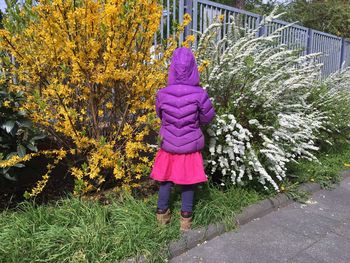 Rear view of woman standing amidst plants during autumn