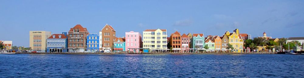 Buildings at waterfront against blue sky