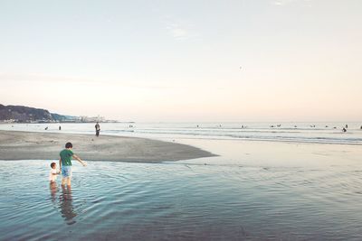 Man and boy standing at sea shore against sky