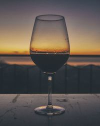 Close-up of beer in glass against sunset sky