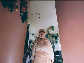 Portrait of woman standing against wall