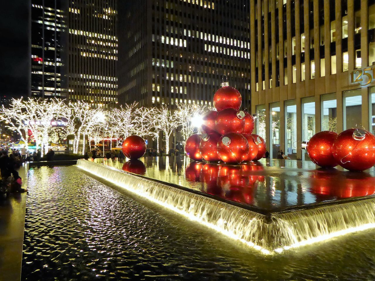 ILLUMINATED FOUNTAIN BY BUILDING AT NIGHT