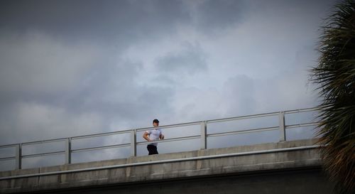 Low angle view of man jogging on bridge