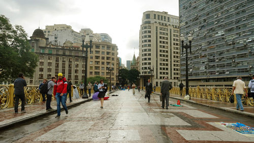 People walking on street amidst buildings in city