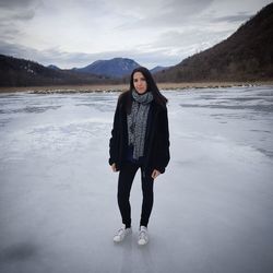 Full length portrait of woman standing on snow against sky