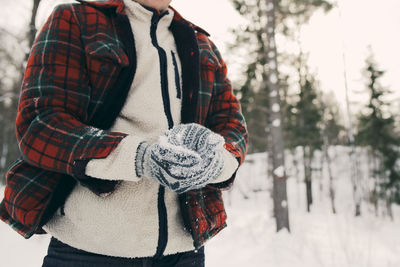 Midsection of man making snowball on snowy field at park