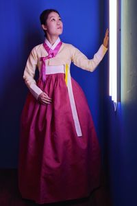 Woman in traditional clothing standing at illuminated room