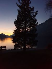 Silhouette tree by lake against sky during sunset