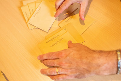 High angle view of hands holding paper at table