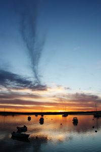 Silhouette boats in sea against sky during sunset