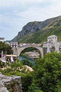 Arch bridge by mountains against sky