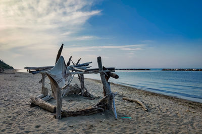 Driftwood on beach against sky